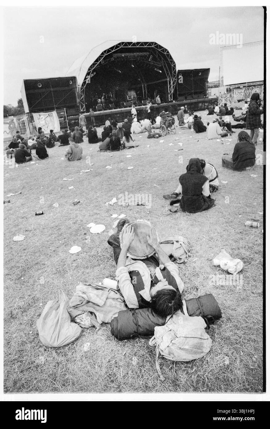 BONGOS, SCHLAGZEUGER, THE DAY AFTER, GLASTONBURY FESTIVAL, 1995: Festivalbesucher hängen herum, während die Bühnen während der Aufräumarbeiten am Montag Morgen nach dem Glastonbury Festival, Pilton Farm, Somerset, England, 26. Juni 1995 abgebaut werden. 1995 feierte das Festival sein 25-jähriges Bestehen. In diesem Jahr gab es keine Pyramidenphase, da sie abgebrannt war. Foto: ROB WATKINS Stockfoto