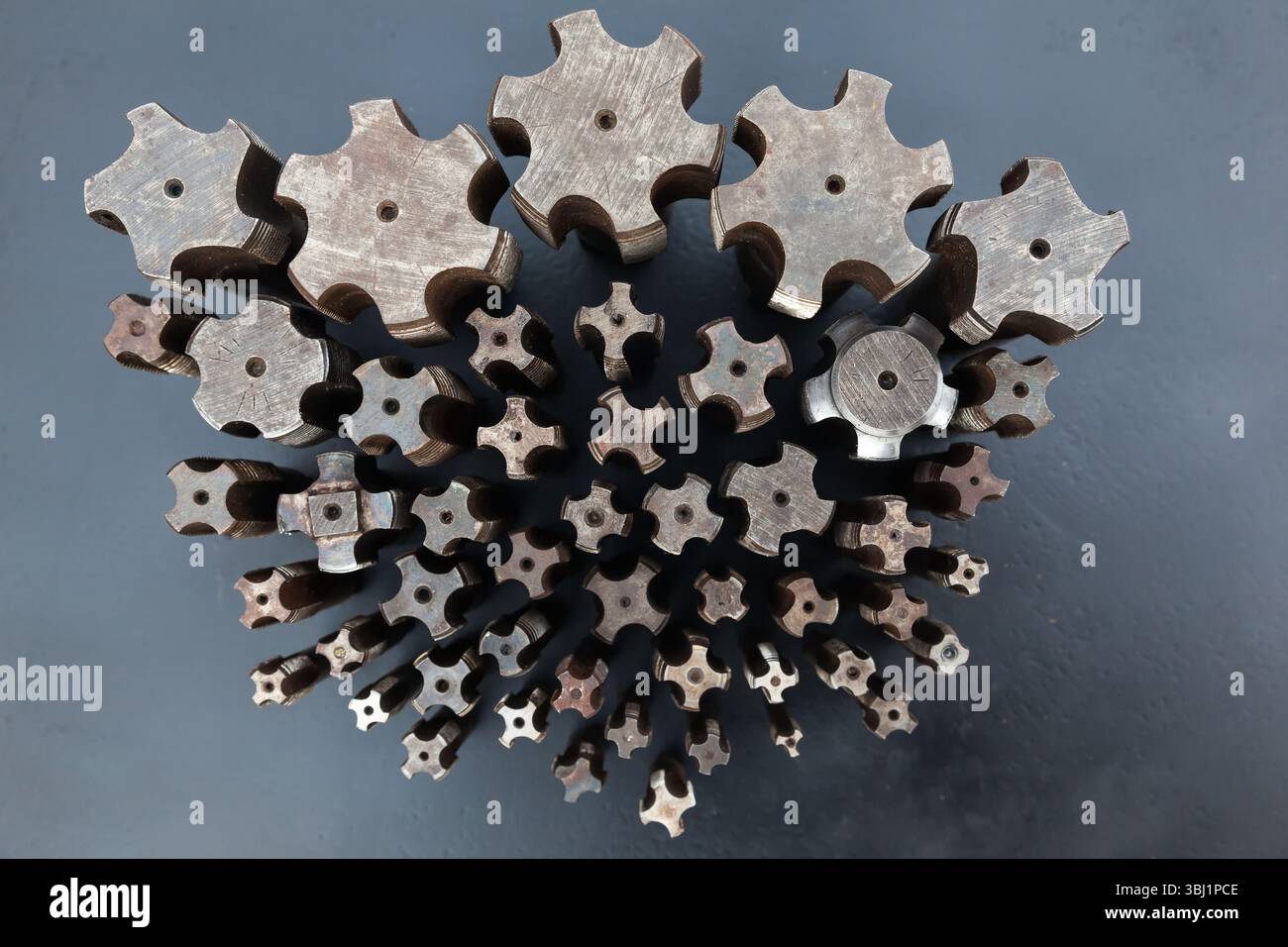 Viele Gewindebohrer unterschiedlicher Größe werden von oben aus auf eine schwarze Oberfläche gestellt. Stockfoto