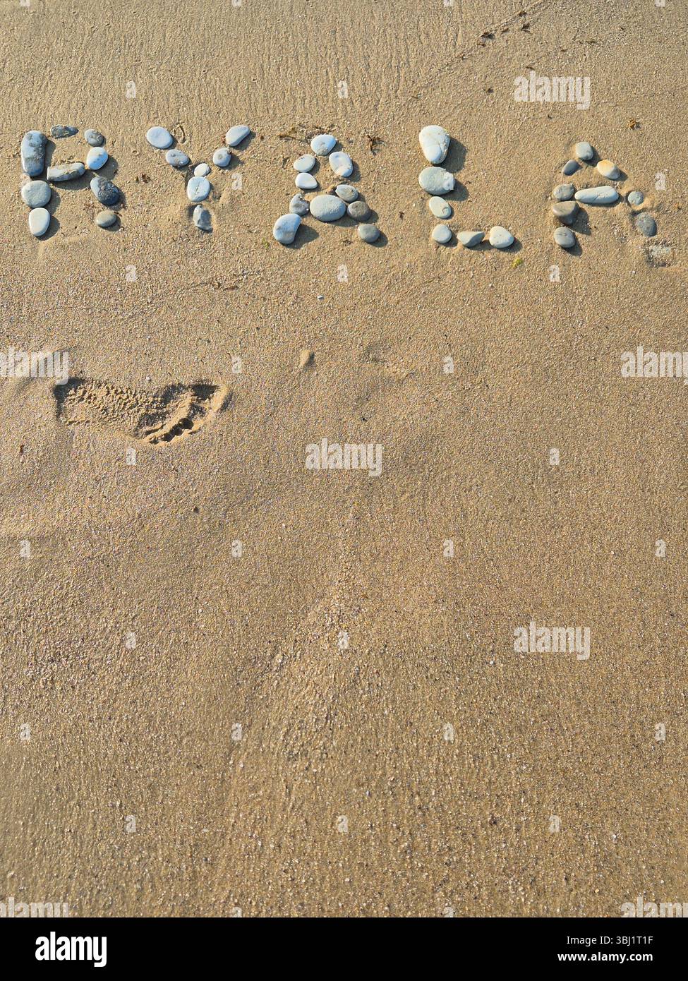 Inschrift auf einem Sandstrand mit Steinen. Inschrift Byala. Ferienort in Bulgarien Stockfoto