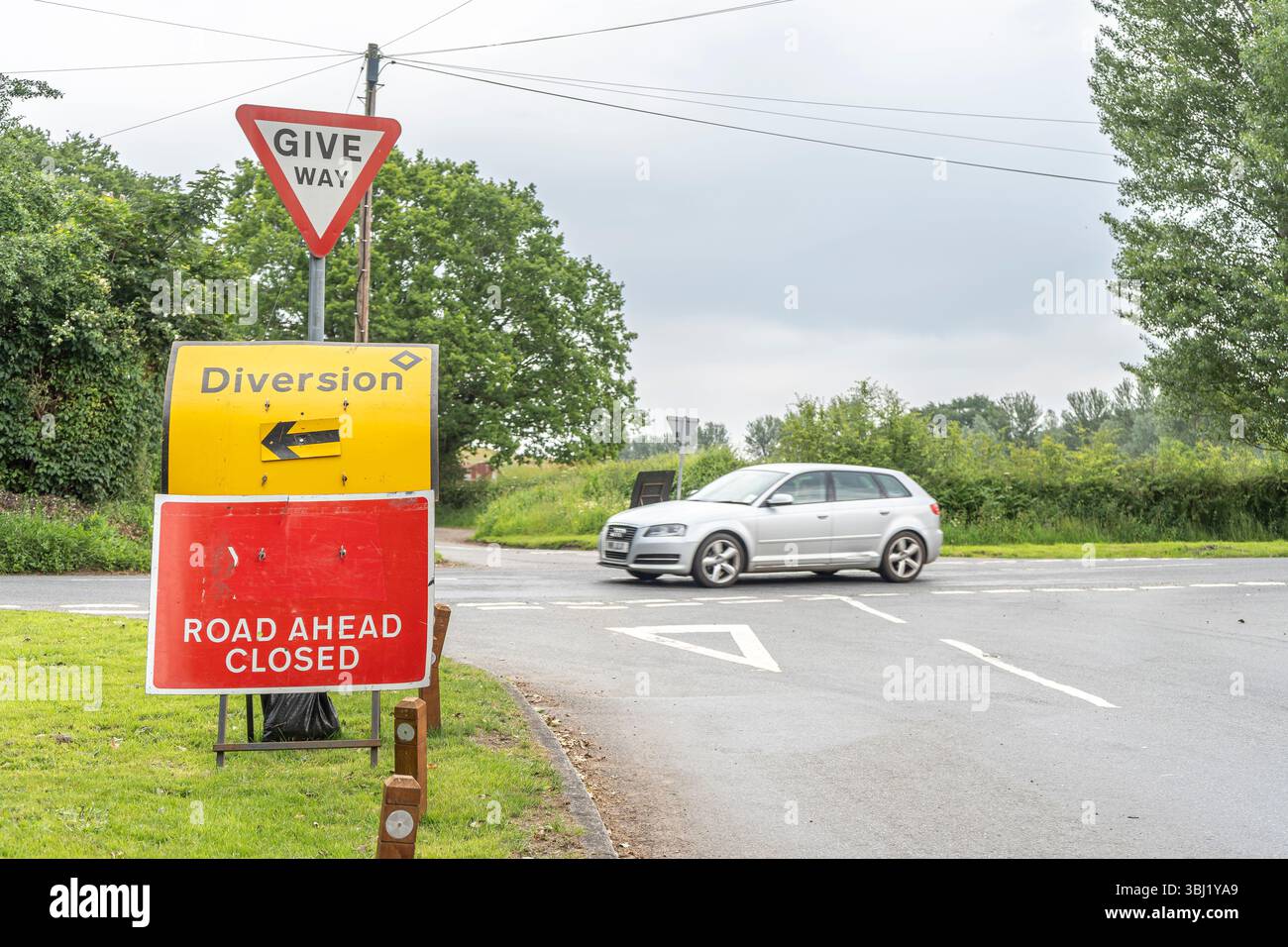 Nahansicht eines Wegweisers vor der Straße, geschlossen, mit Abzweigpfeilschild. Stockfoto