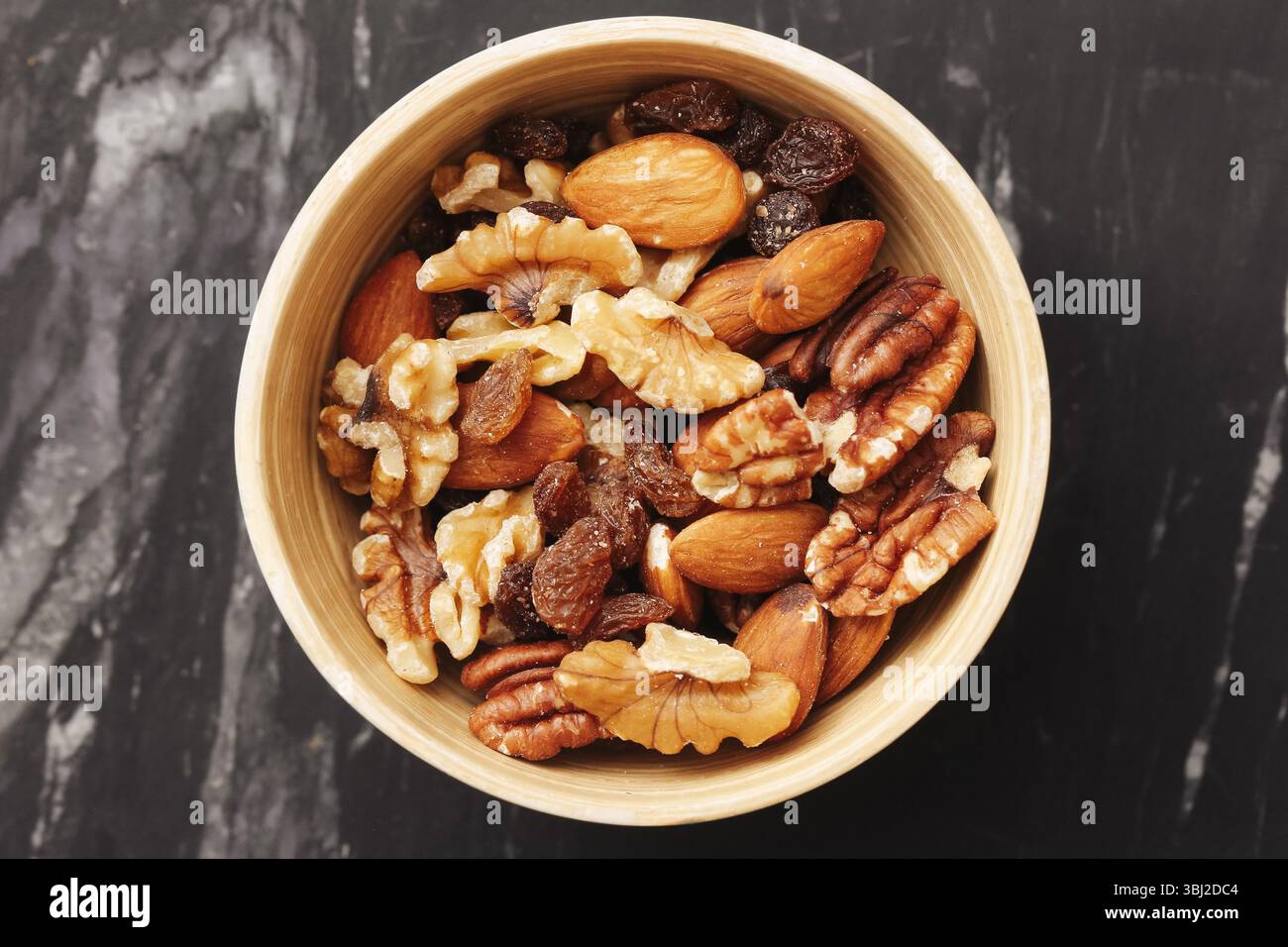 Verschiedene Nüsse in rustikaler Schüssel. Walnüsse Cashews Pekannüsse und Rosinen. Gesunder Bio-Snack. Gemischte trockene Früchte und Nüsse. Proteinreiche vegetarische Nahrung. Stockfoto