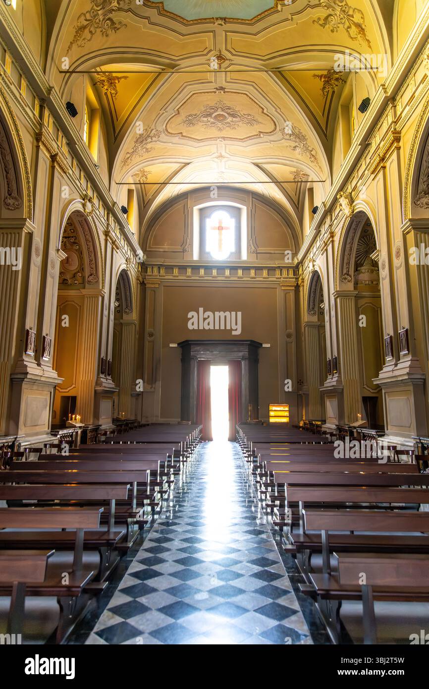 Gravedona, Lombardei - Italien - 24.06.2024: Das Innere der Chiesa di San Vincenzo hebt ein Kreuz und einen Altar hervor, umgeben von hohen, verzierten Mauern und einem Stockfoto