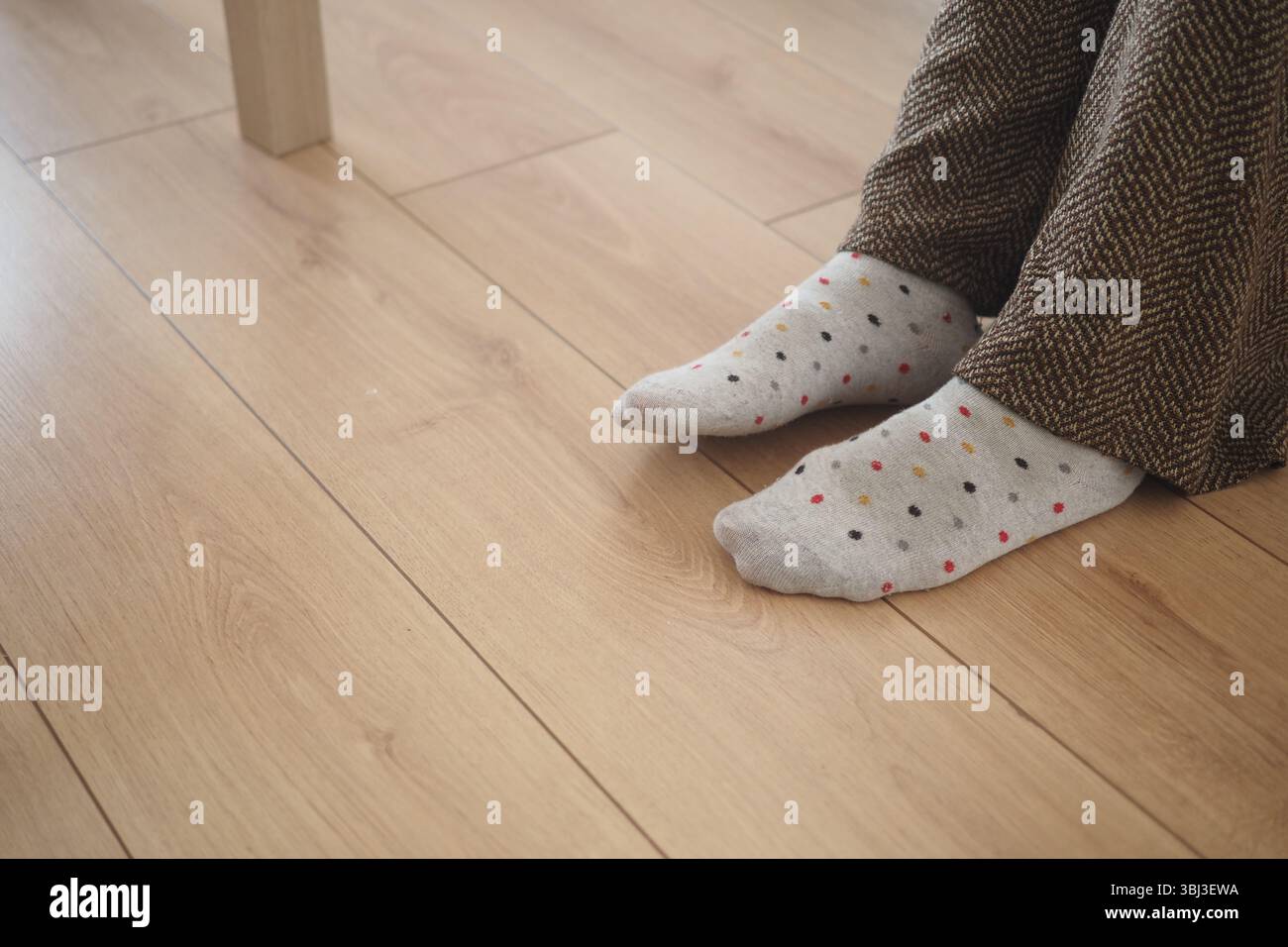 Gemütliche Füße in gemusterten Socken auf Holzboden Stockfoto