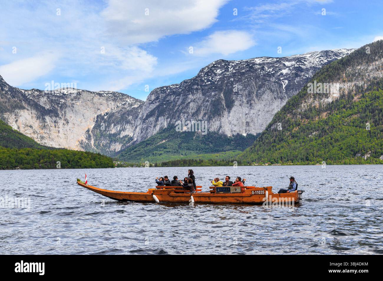 HALLSTATT, ÖSTERREICH - 18. MAI 2021: Eine Gruppe nicht identifizierter Touristen macht eine Bootsfahrt auf dem Hallstetter See. Stockfoto HALLSTATT, ÖSTERREICH - 18. MAI 2021: Eine Gruppe nicht identifizierter Touristen macht eine Bootsfahrt auf dem Hallstetter See. Stockfoto