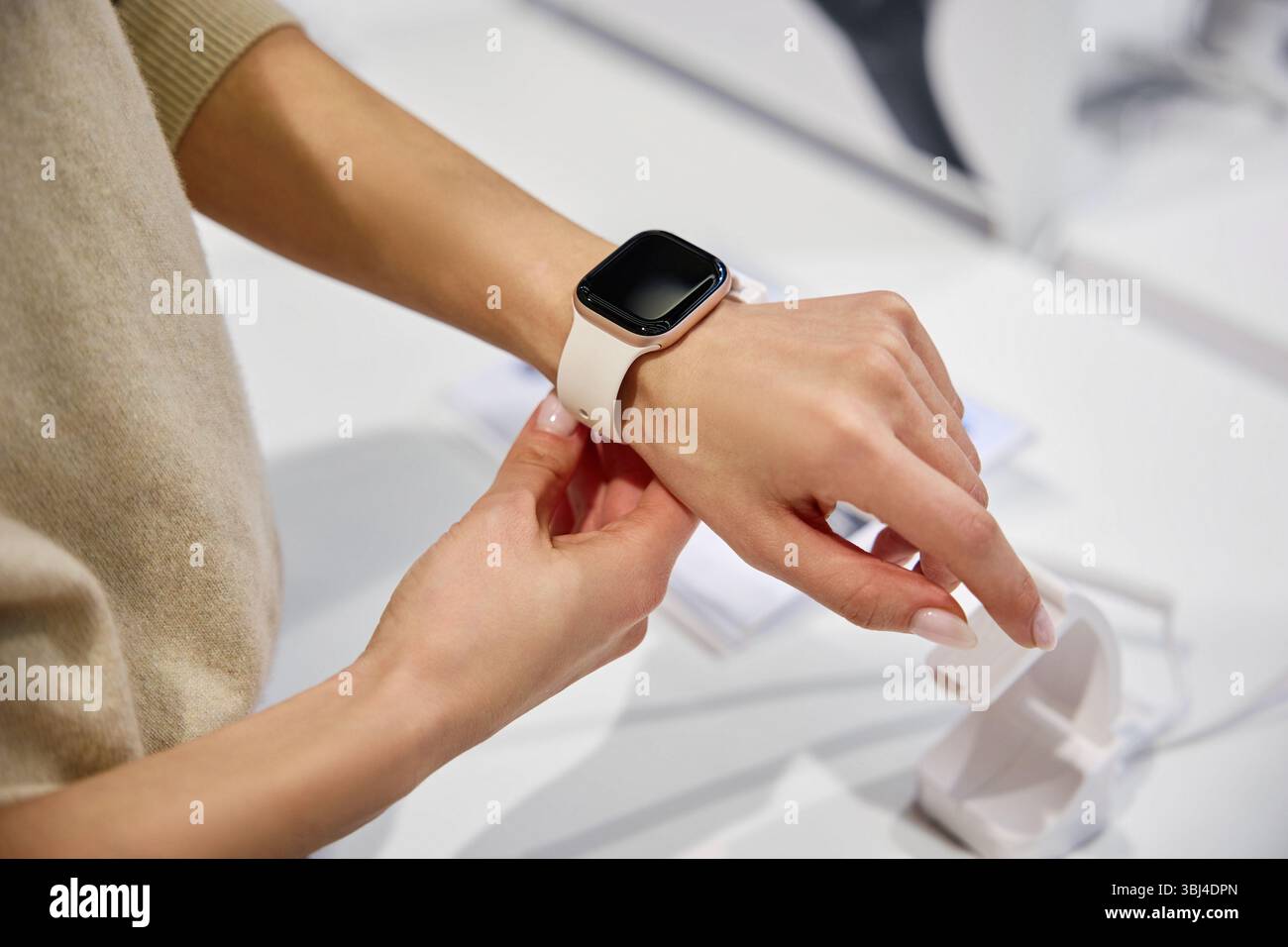 In einem modernen Einzelhandelsgeschäft untersucht eine Frau eine stilvolle Smartwatch am Handgelenk und vereint dabei innovative Technologie mit moderner Mode in einem eleganten Gerät Stockfoto