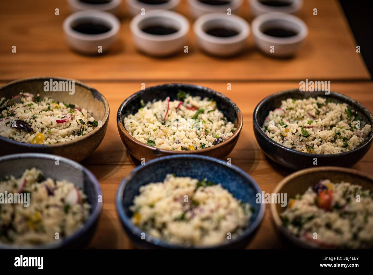 Gourmet Couscous Tasting Setup mit kleinen Saucen auf Holztisch Stockfoto
