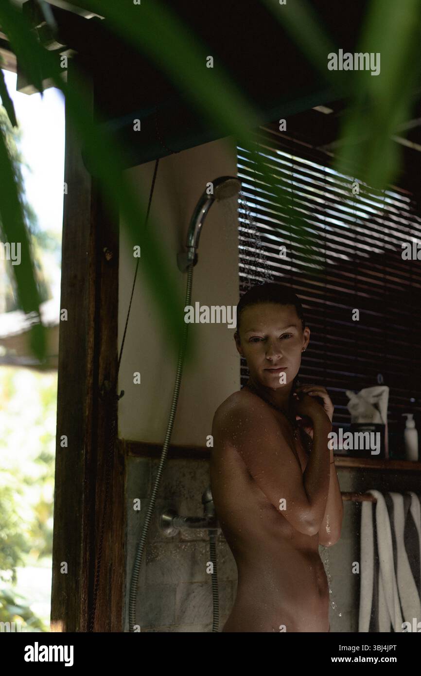 Frau, die eine ruhige Dusche in einem tropischen Außenbad nimmt Stockfoto