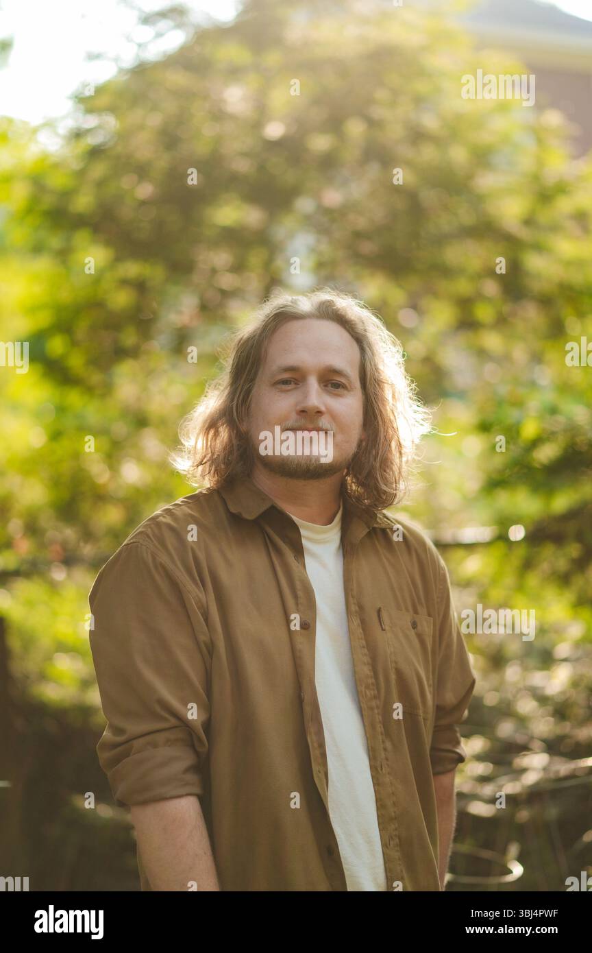 Mann mit langen Haaren, der draußen steht Stockfoto