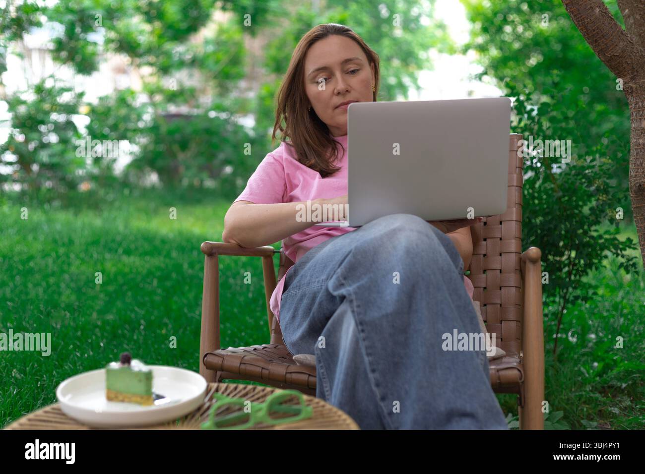 Frau mit ihrem Laptop, die Natur und Produktivität miteinander verbindet Stockfoto