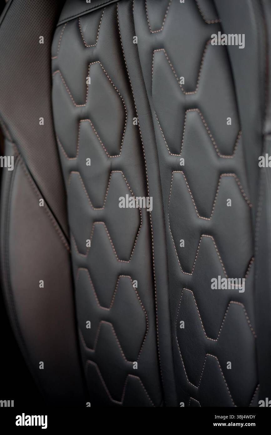Vordersitz aus Leder in einem Auto. Moderne, schwarze Ledersitze im SUV-Interieur mit Bronzefarben. Stockfoto
