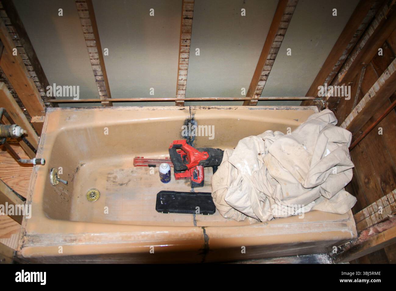 Das unrenovierte Badezimmer zeigt eine Badewanne mit Werkzeug für die Renovierung. Stockfoto