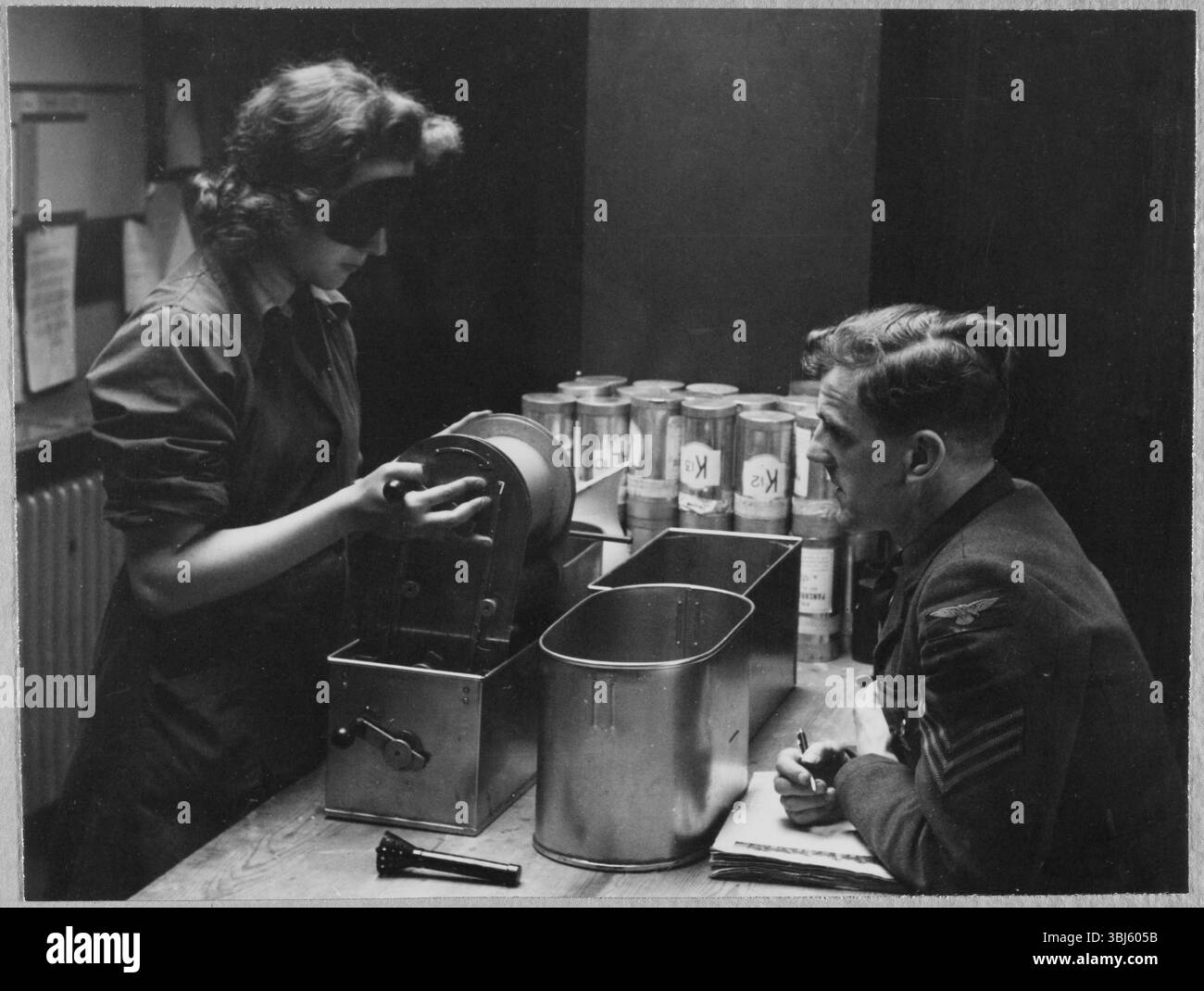Royal Air Force No. 2 School of Photography, Palatine Road, Blackpool, Lancashire, 1942-1943. Eine Auszubildende der Women's Auxiliary Air Force (WAAF), die während der Prüfung auf dem Trade Test Board am Ende des Schulungskurses mit einer Augenmaske eine Rolle fotografischen Films bearbeitet, während sie eine Augenmaske trägt, um die Arbeit im Dunkeln zu simulieren. Die RAF’s No. 2 School of Photography wurde im August 1940 gegründet, um den schnell wachsenden Bedarf an Fotografen und Fototechnikern zu decken, die während des Zweiten Weltkriegs bei der Luftaufklärung helfen sollten. Die Schule war am Blackpool Technical College und am Palatine Second untergebracht Stockfoto