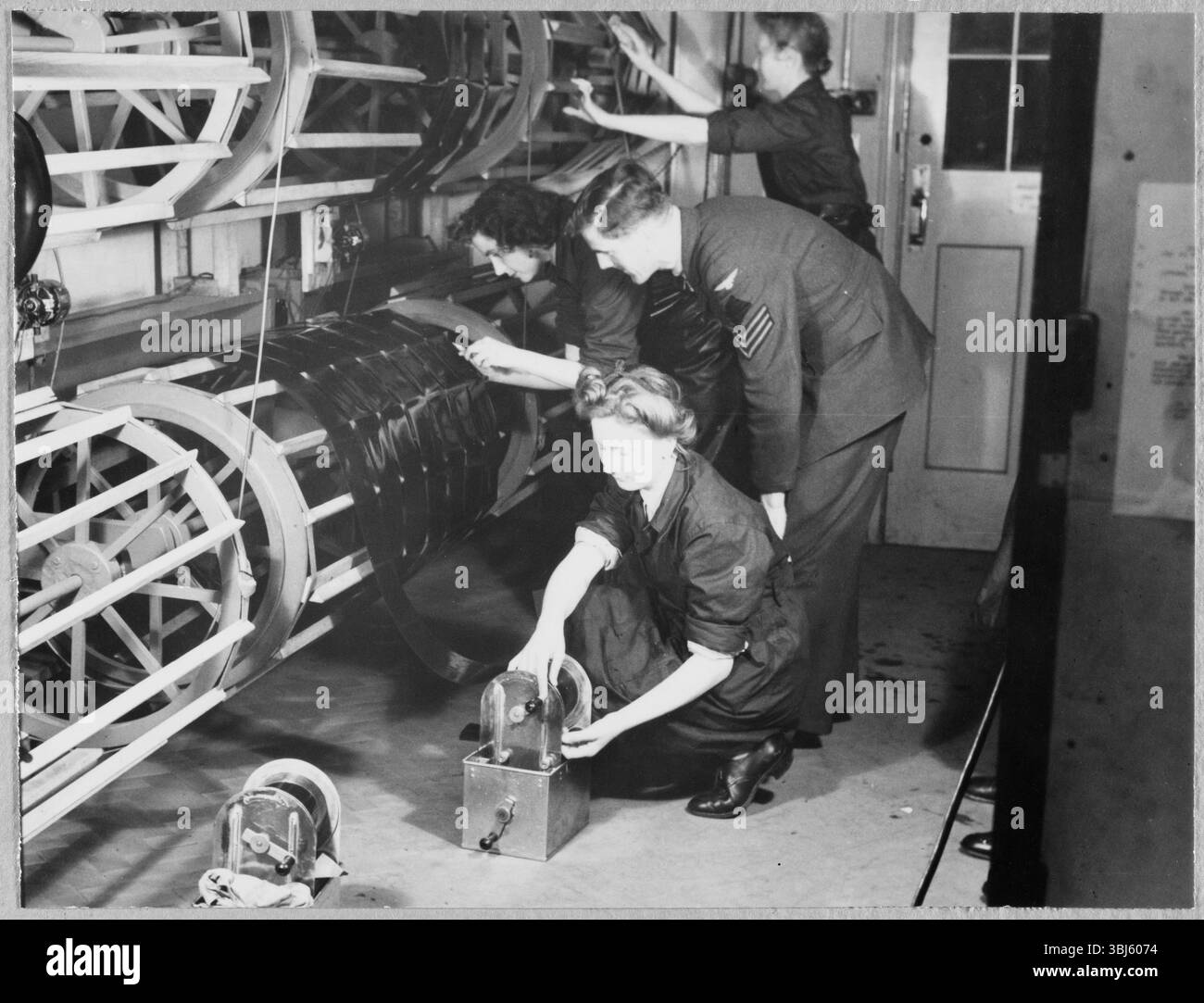 Royal Air Force No. 2 School of Photography, Palatine Road, Blackpool, Lancashire, 1942-1943. Ein RAF-Ausbilder beobachtet, wie Auszubildende der Women's Auxiliary Air Force (WAAF) fotografische Filme auf die Trockentrommeln legen. Die RAF&#x2019;s No. 2 School of Photography wurde im August 1940 gegründet, um den schnell wachsenden Bedarf an Fotografen und Fototechnikern zu decken, die während des Zweiten Weltkriegs bei der Luftaufklärung helfen sollten. Die Schule war am Blackpool Technical College und der Palatine Secondary School in Blackpool angesiedelt. Die Ausbildung von Frauen an der Schule begann 1941. Dieses Foto ist eins von Stockfoto