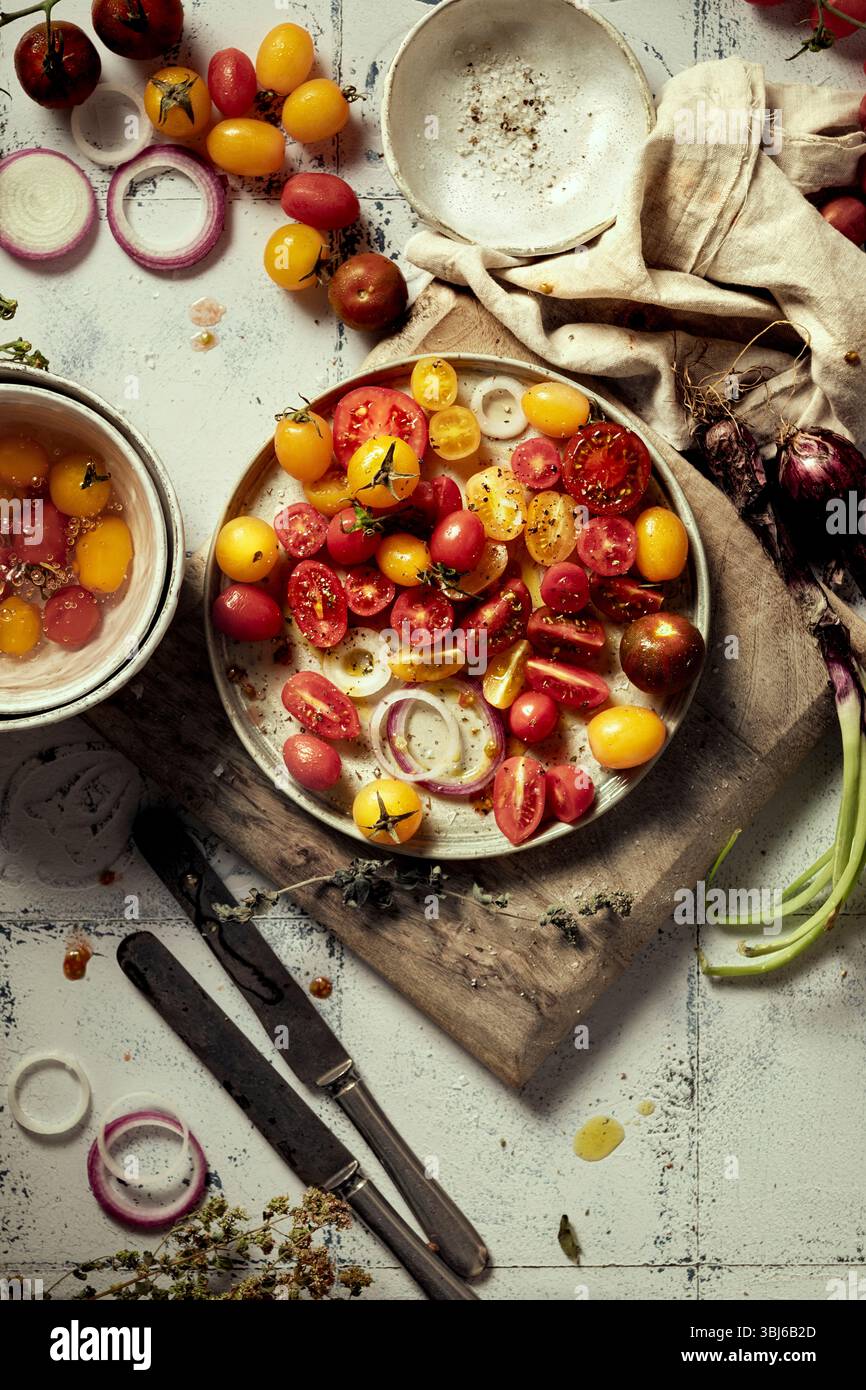 Verschiedene Arten von frischen italienischen Tomaten und Zwiebeln mit Kräutern Stockfoto