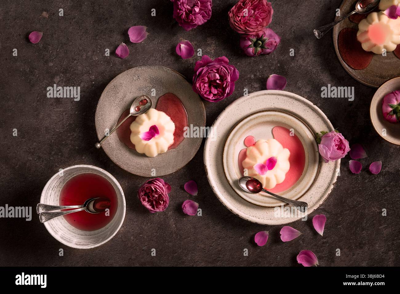 Panna Cotta auf Tellern mit Rosenblättern und Rosensirup Stockfoto