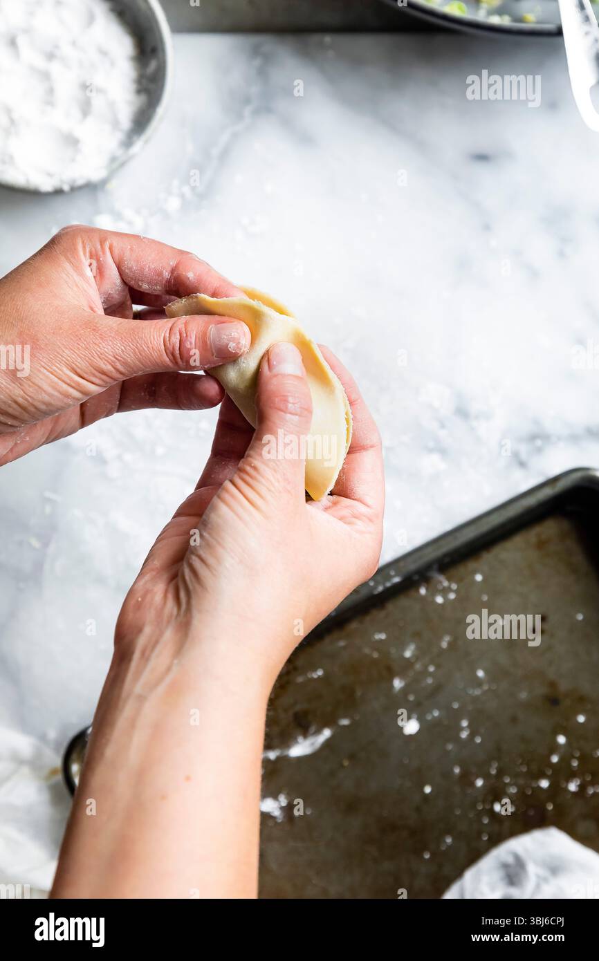 Eine Person macht auf einer bemehlten Oberfläche Knödel. Stockfoto