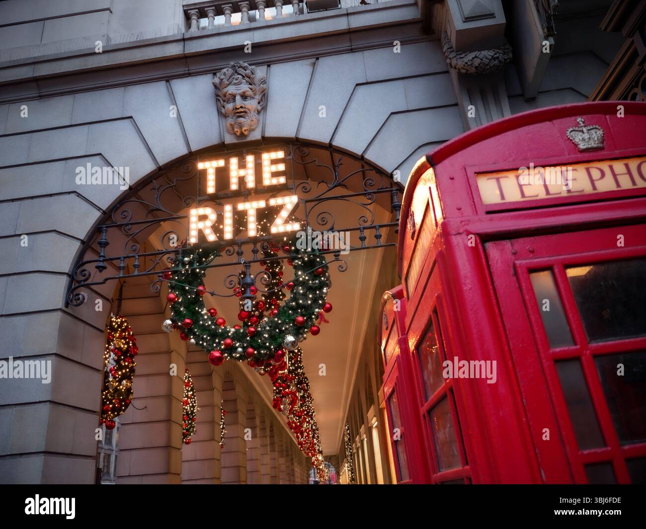 Das Ritz Hotel LONDON Weihnachtskranz dekoriert Piccadilly Christmas mit traditionellen, funktionierenden roten Telefonboxen im Vordergrund Londons, Großbritannien Stockfoto