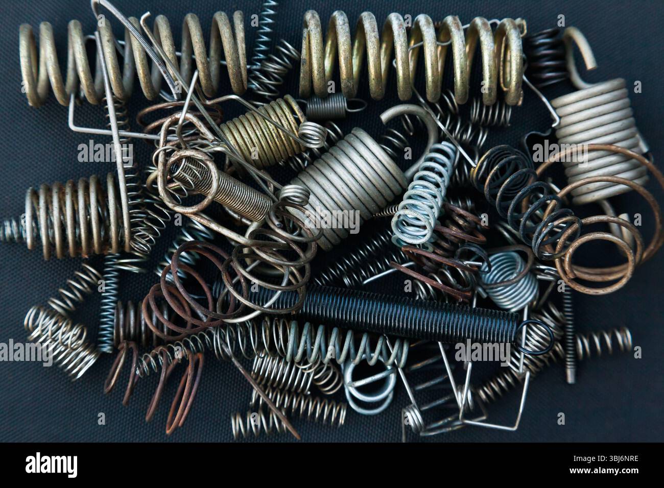 Viele kleine Federn unterschiedlicher Größe liegen auf einem Haufen vor schwarzem Hintergrund. Stockfoto