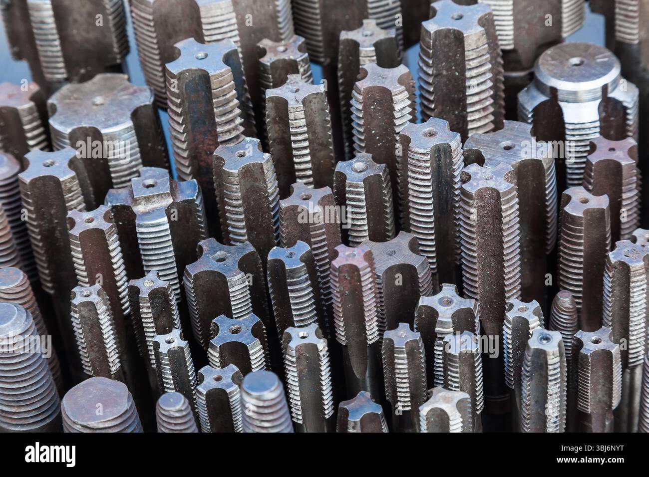 Viele Gewindebohrer unterschiedlicher Größe werden von oben aus auf eine schwarze Oberfläche gestellt. Stockfoto