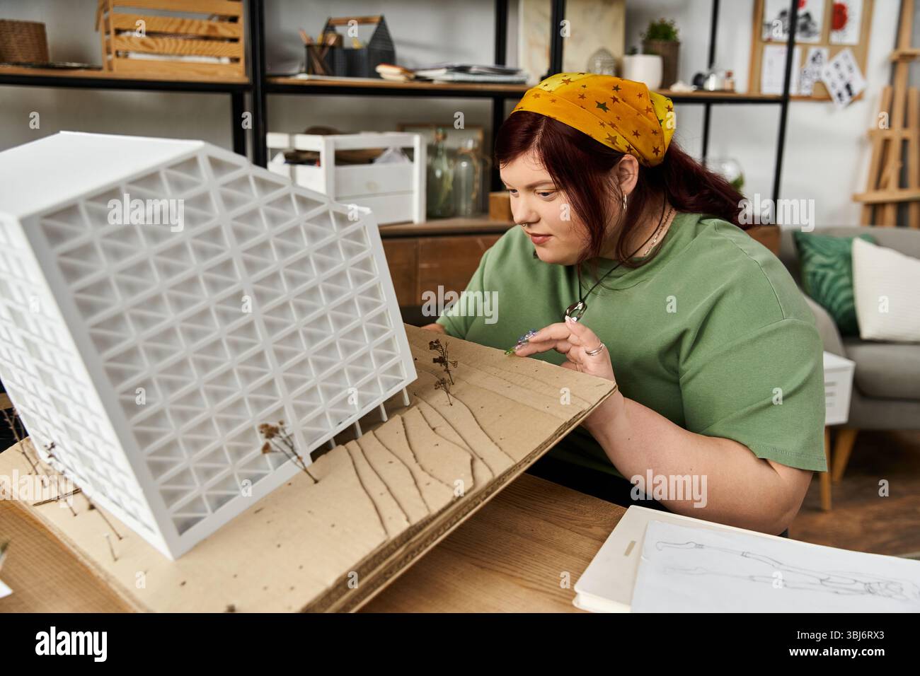 Eine hübsche Frau zeigt ihre Kreativität, indem sie ein Architekturmodell in einem schicken Studio baut. Stockfoto