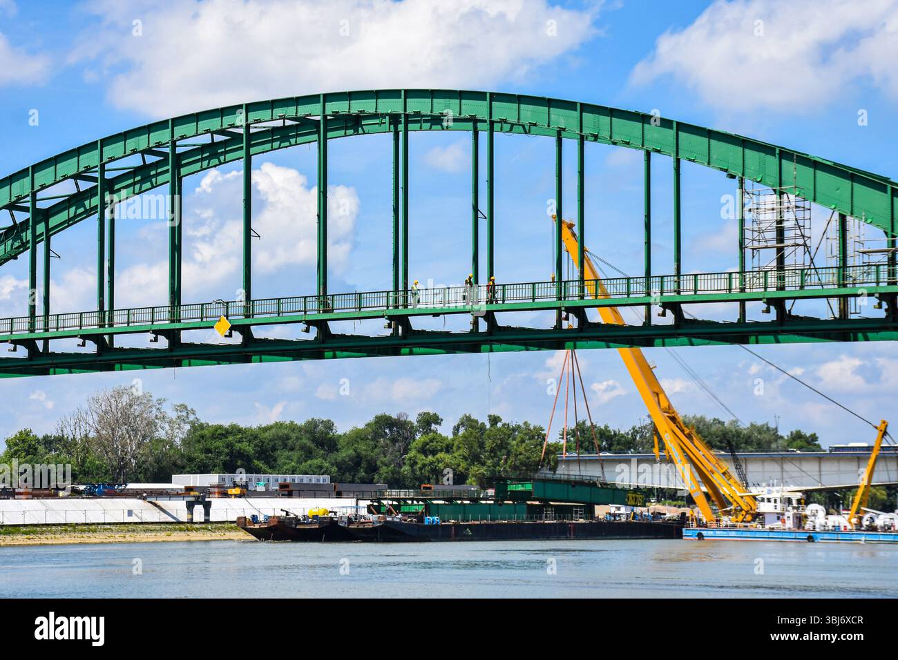 Detailansicht von Arbeitern, die eine alte grüne Stahlbahnbrücke im Rahmen eines historischen Ingenieurprojekts dekonstruieren. Detailansicht der Arbeiter-Dekonstruktion Stockfoto