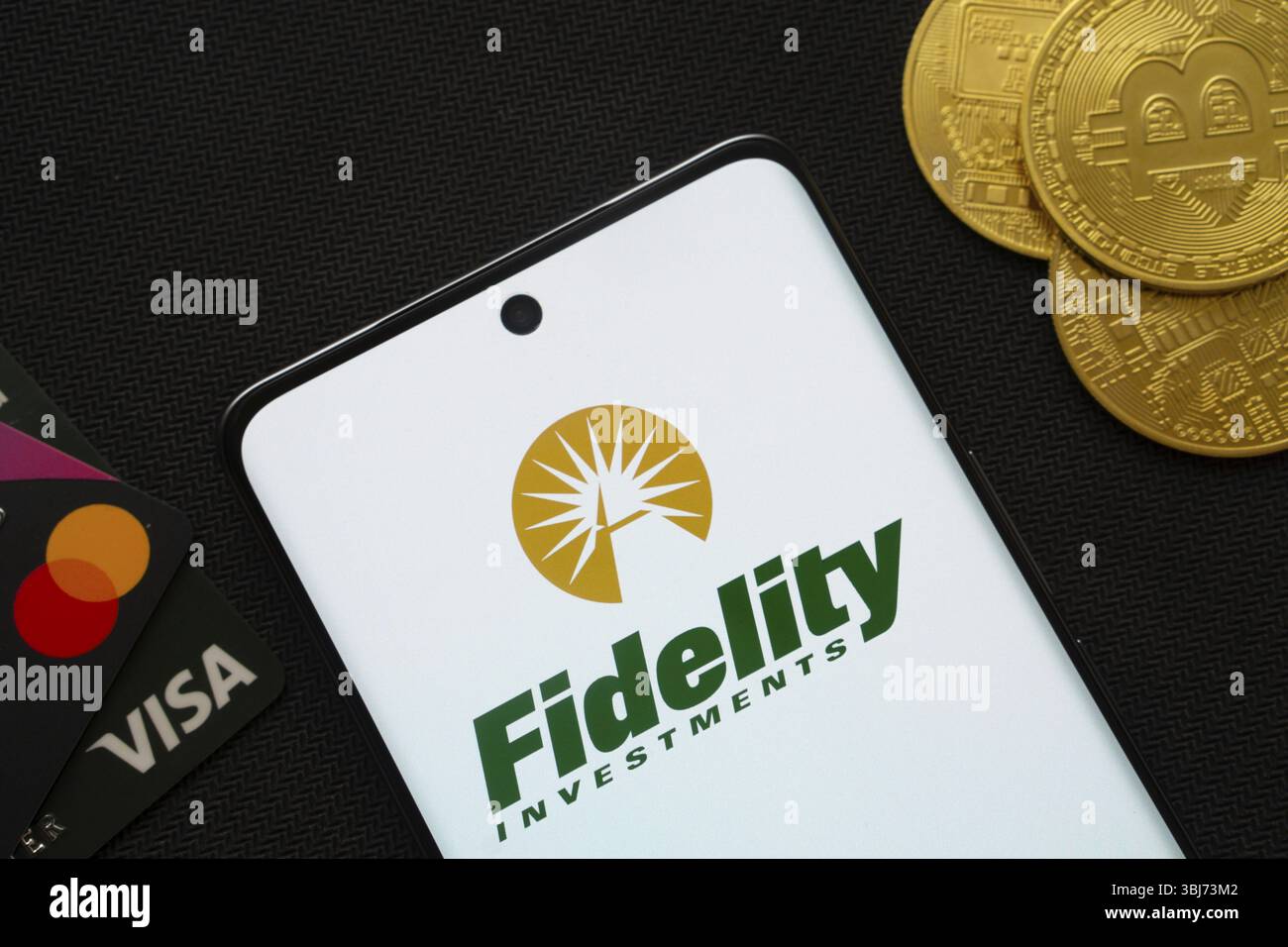 Dhaka, Bangladesch, 12. Juni 2025: Smartphone mit Fidelity Investments Logo umgeben von Bitcoin-Münzen und Zahlungskarten Stockfoto