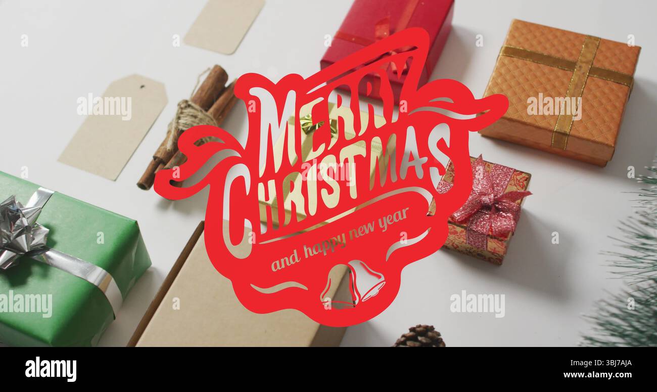 Geschenkboxen mit Zimtstäbchen und Tannenzapfen in roter Begrüßungsgrafik auf weißer Tischplatte Stockfoto