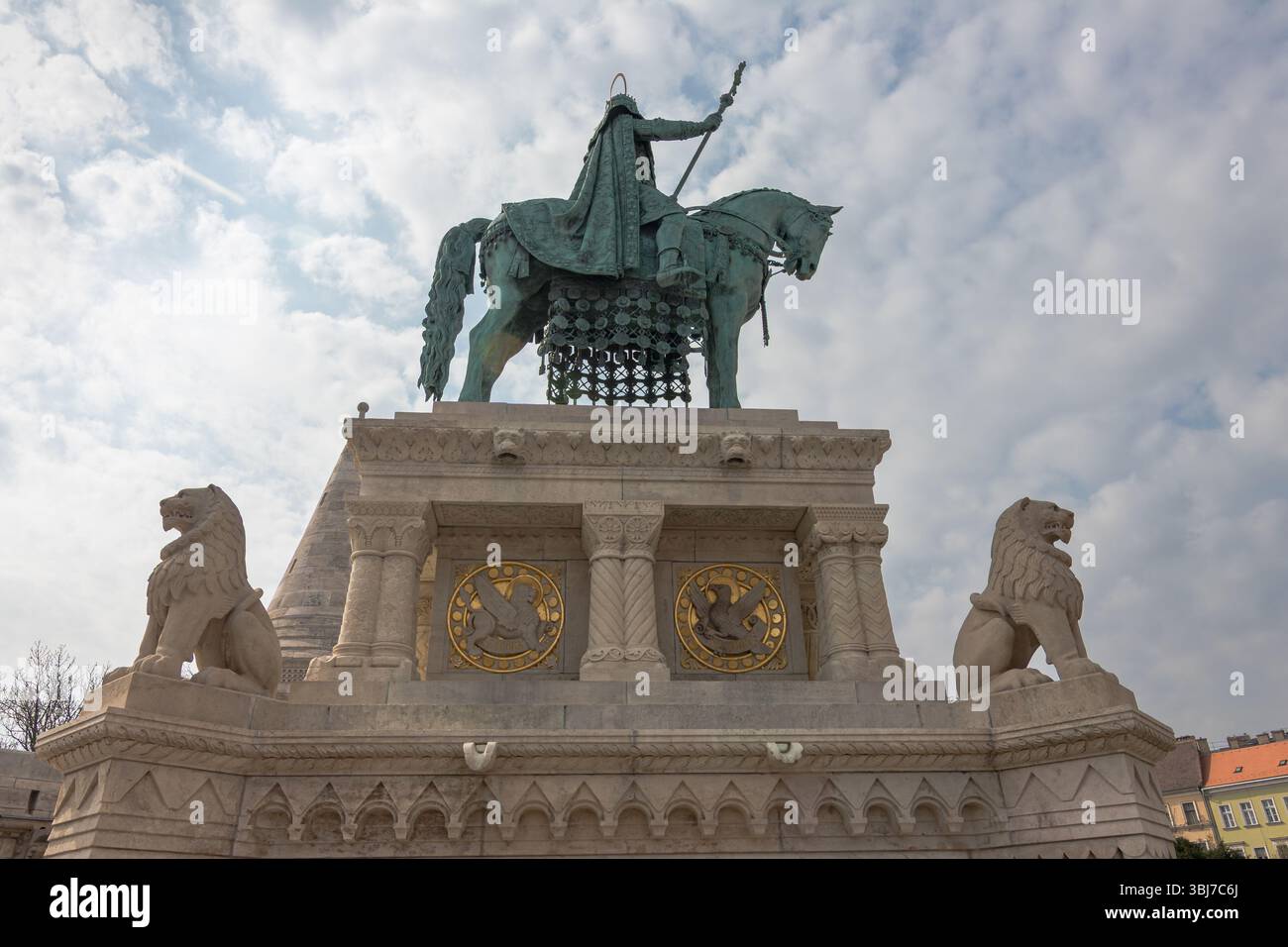BUDAPEST, UNGARN, 04.07.2018: Eine historische Skulptur, die eine montierte Figur auf einem verzierten Sockel darstellt, flankiert von Löwenstatuen, die gegen eine teilweise Wolke gestellt ist Stockfoto