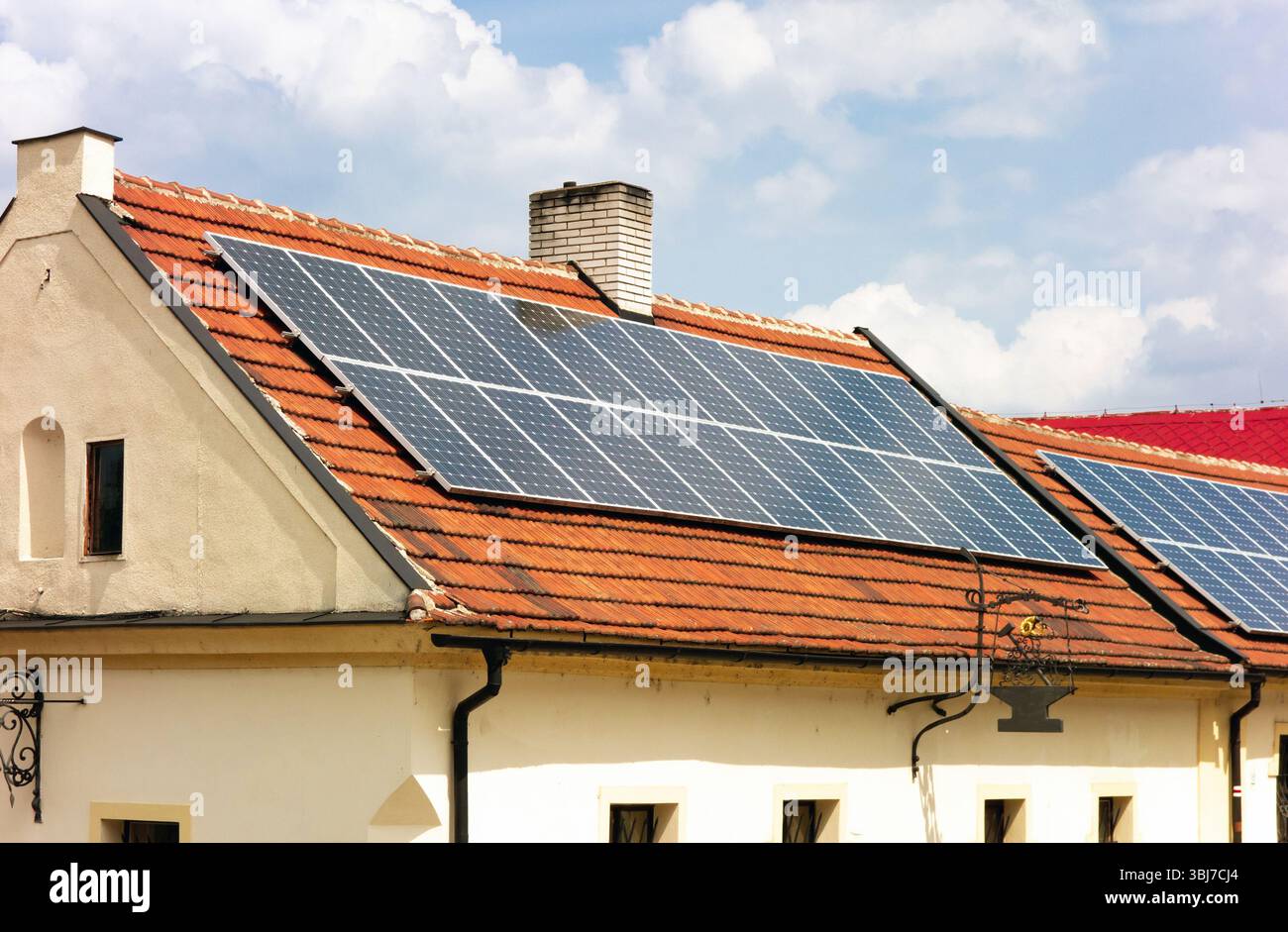 Kontrast zwischen dem alten Haus und der modernen Technologie, da es Solardach zur Erzeugung sauberen Stroms nutzt Stockfoto