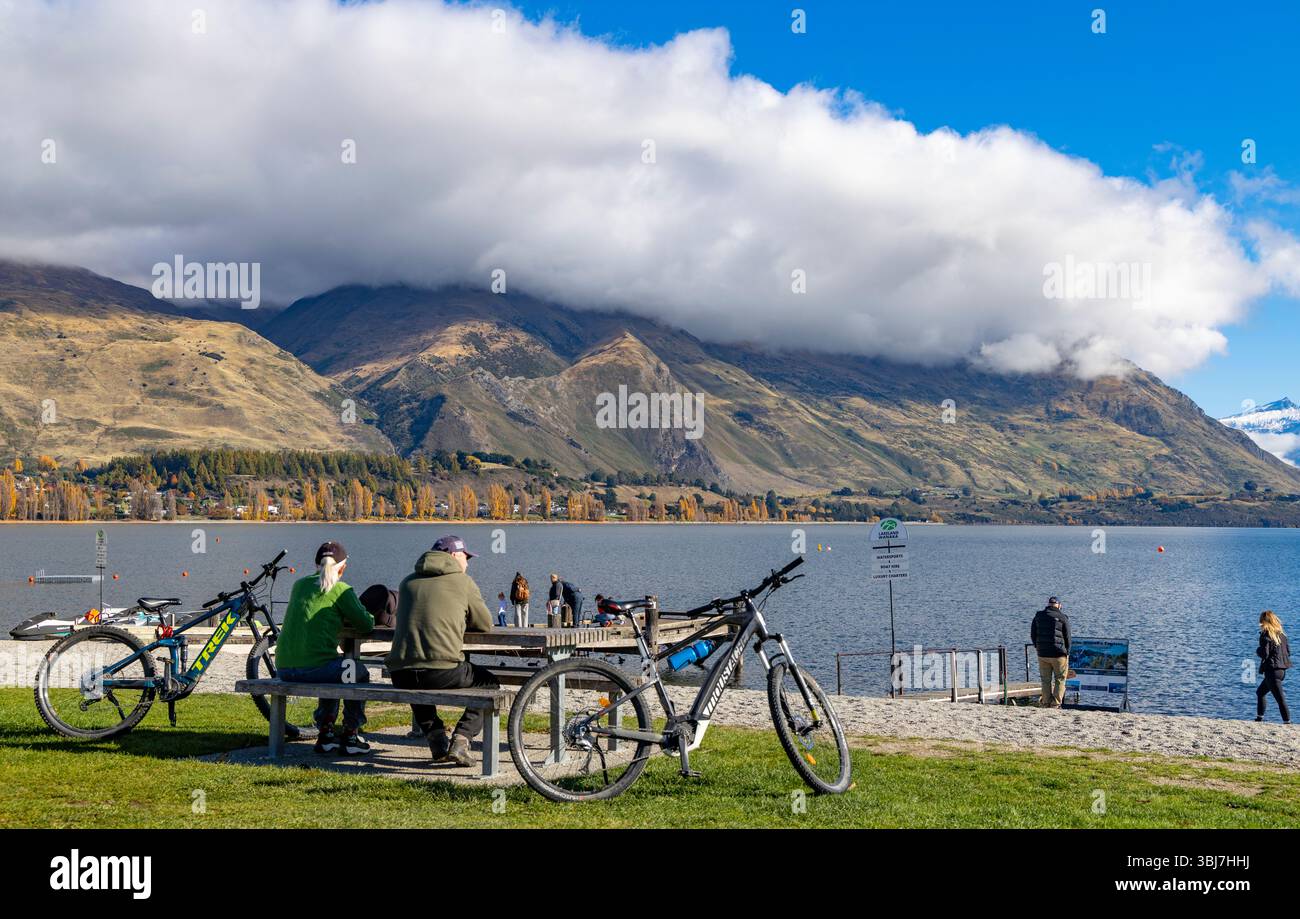 Wanaka, Otago, South Island, Neuseeland, Paare mittleren Alters parken ihre Mountainbikes, um den Blick auf den Lake Wanaka zu genießen Stockfoto