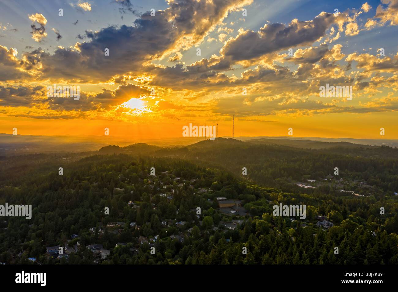 Portland, Oregon - 12. Juni 2019: Sonnenuntergang über den West Hills. Die Sonnenstrahlen strömen durch die Wolken und beleuchten die Landschaft und die Stadt darunter Stockfoto