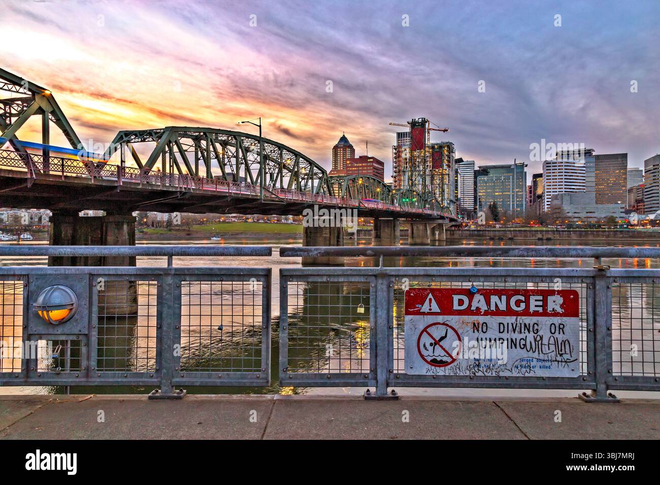 Hawthorne Bridge, Portland, Oregon – 9. Januar 2019: Ein Zug überquert die Hawthorne Bridge bei Sonnenuntergang mit einem Schild „No Diving or Jumping“. Stockfoto