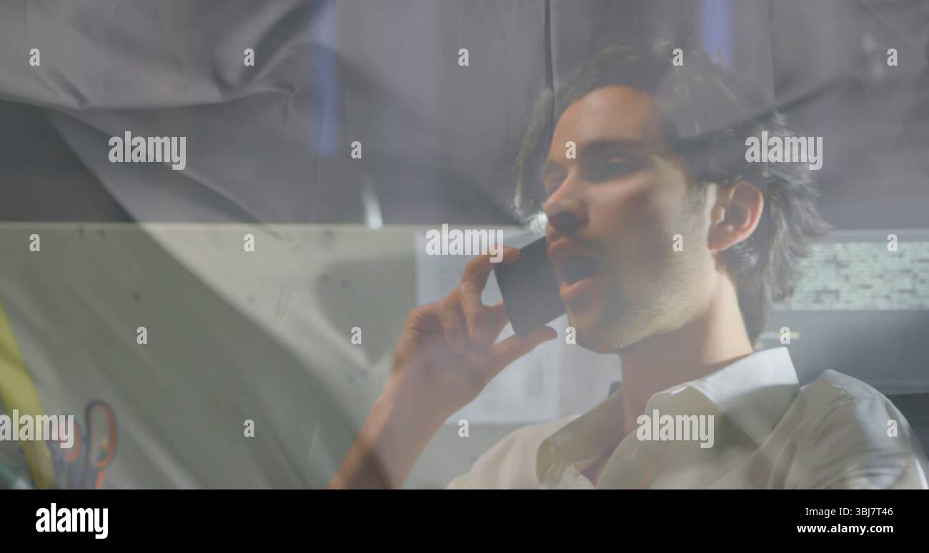 Sprechender Geschäftsmann mit Smartphone am Schreibtisch im Büro mit Monitor und Stifthalter, Kopierraum Stockfoto