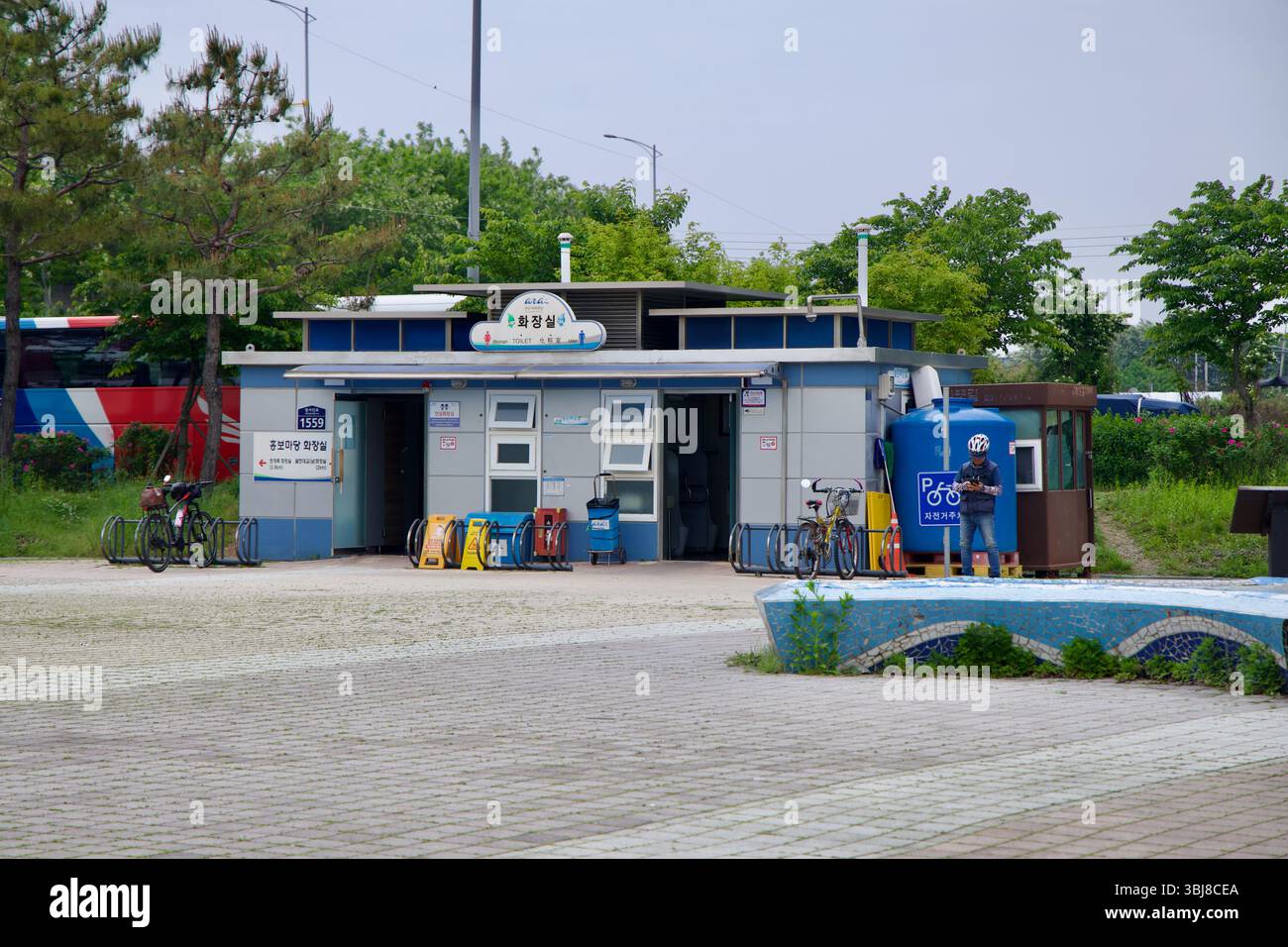 Incheon, Südkorea - 19. Mai 2025: Ein Radfahrer hält neben der Toilette und dem Fahrradreparaturbereich an der Ara West Sea Lock Plaza, einer wichtigen Haltestelle entlang der A Stockfoto