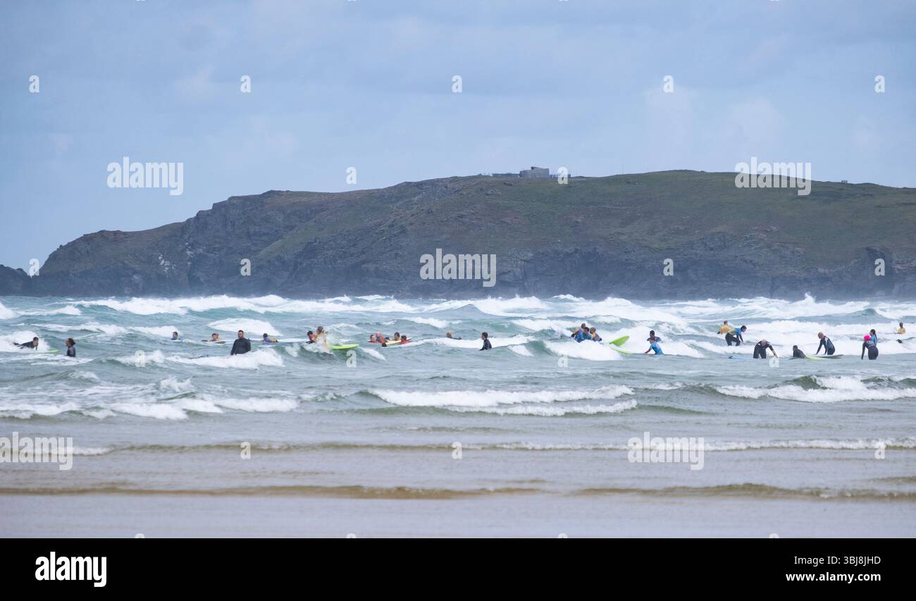 Surfer und Schwimmer im rauen Meer an einem windigen Tag im beliebten Urlaubsziel Perranporth, Cornwall, England. Stockfoto