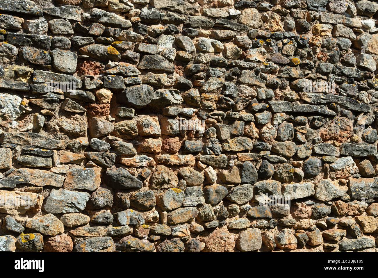 Eine verwitterte Steinwand zeigt eine Mischung aus Farben und Texturen Stockfoto