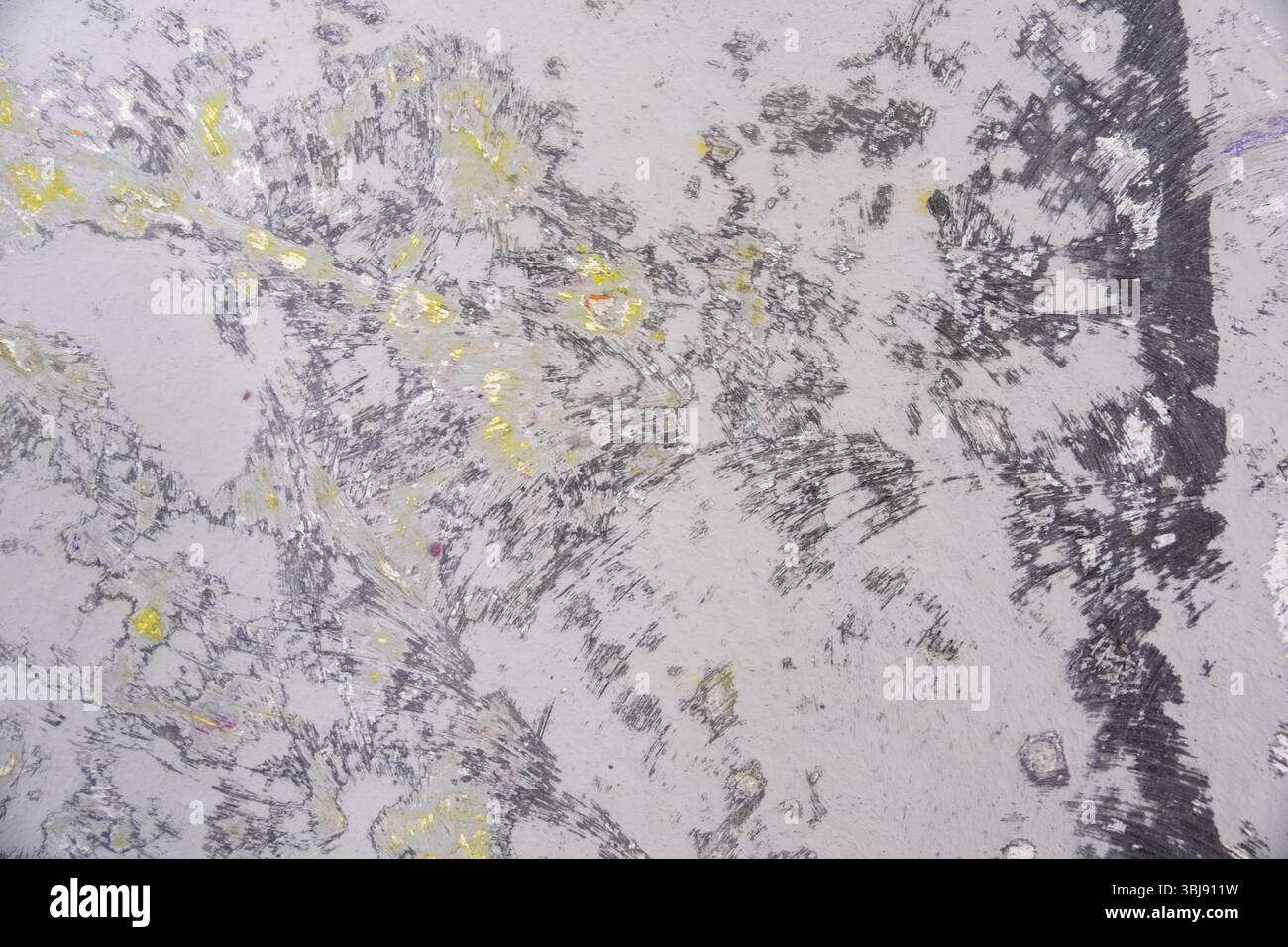 Der geschliffene Studioboden zeigt ein abstraktes Muster aus mehrschichtiger Farbe früherer Bodypainting-Shootings. Die graue Basis ist mit dynamischen Texturen in Bla gekennzeichnet Stockfoto