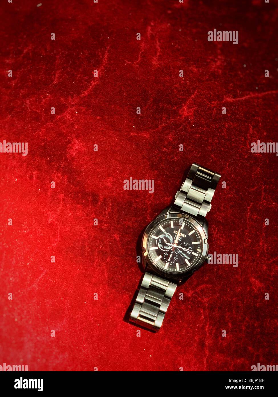 Eine Uhr aus Edelstahl auf einem roten Teppich. - Smartphone-aufgenommenes Stockfoto