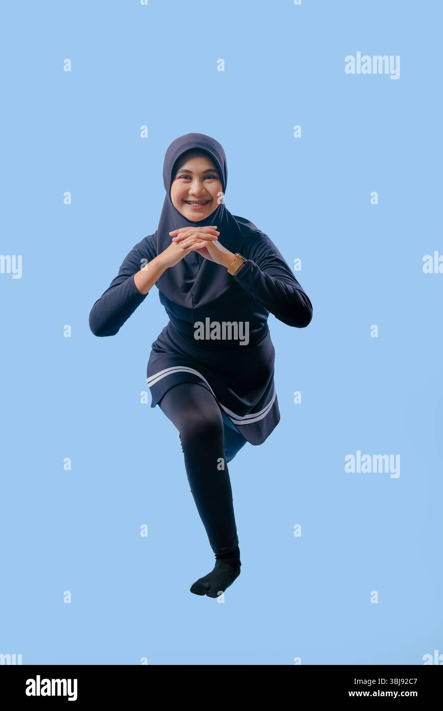 Eine Frau in einem schwarzen Outfit macht eine Yoga-Pose. Sie trägt einen schwarzen Rock und schwarze Socken Stockfoto