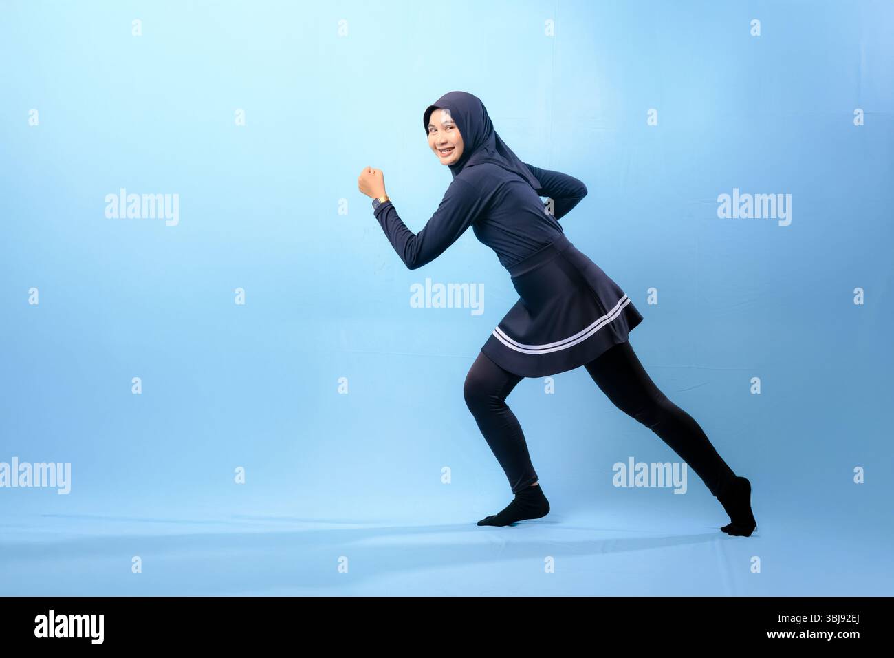 Eine Frau in schwarz-weißem Outfit rennt. Konzept der Entschlossenheit und Konzentration, während die Frau sich dazu drängt, schneller zu laufen Stockfoto