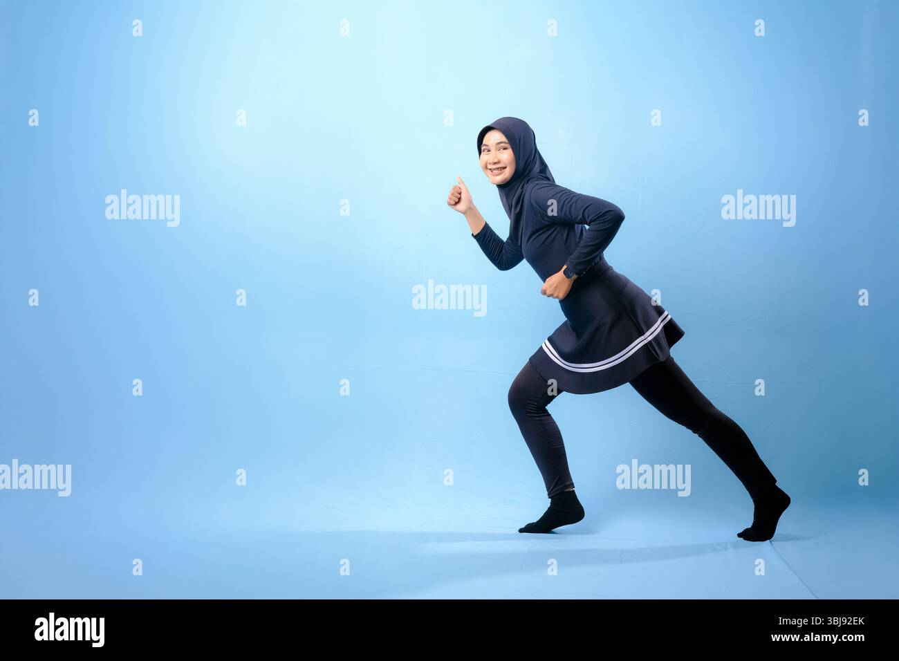 Eine Frau in schwarz-weißem Outfit rennt. Konzept der Entschlossenheit und Konzentration, während die Frau sich dazu drängt, schneller zu laufen Stockfoto