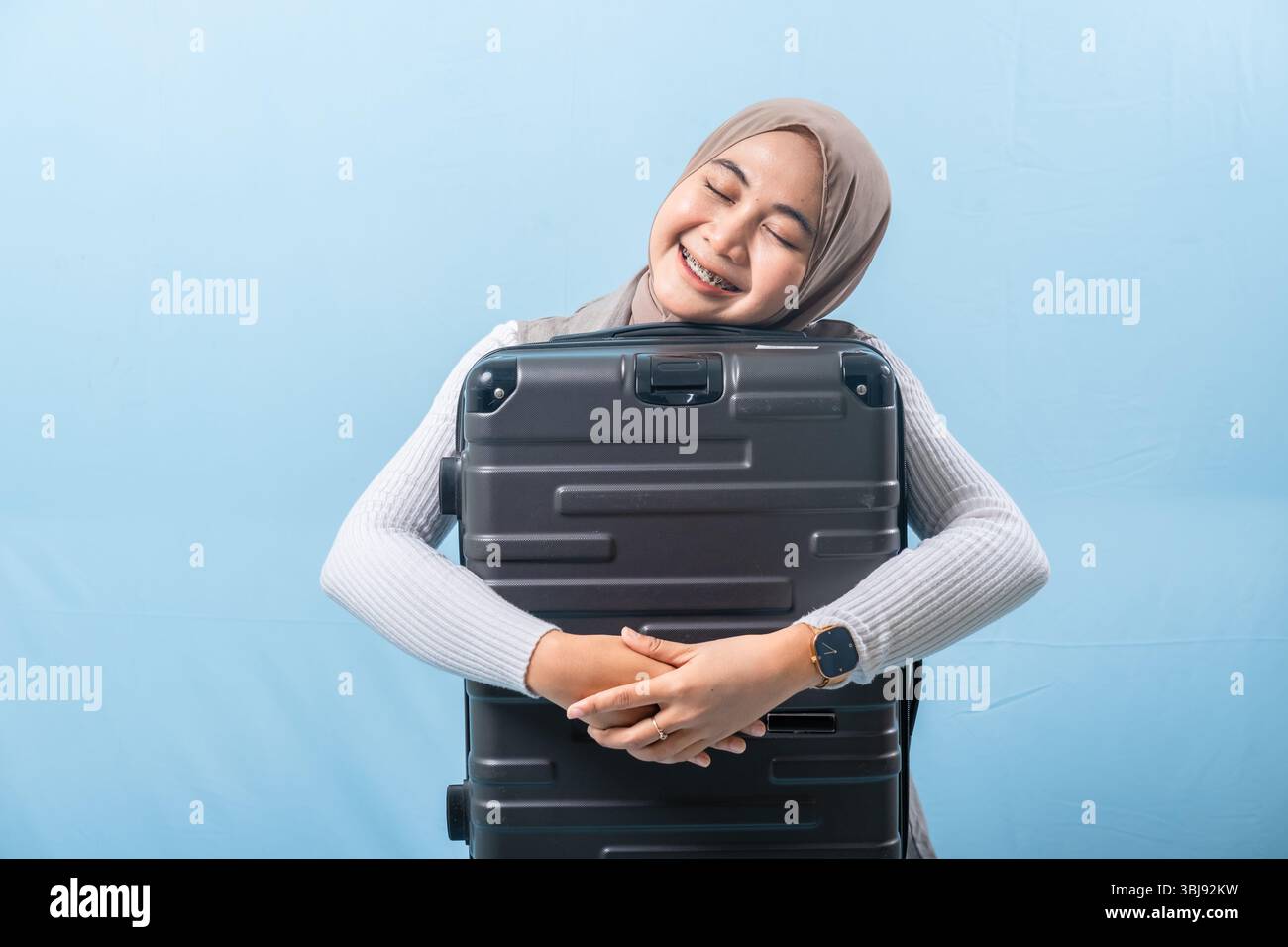 Eine Frau hält einen schwarzen Koffer und lächelt. Konzept von Abenteuer und Spannung, während die Frau sich auf eine Reise vorbereitet. Stockfoto