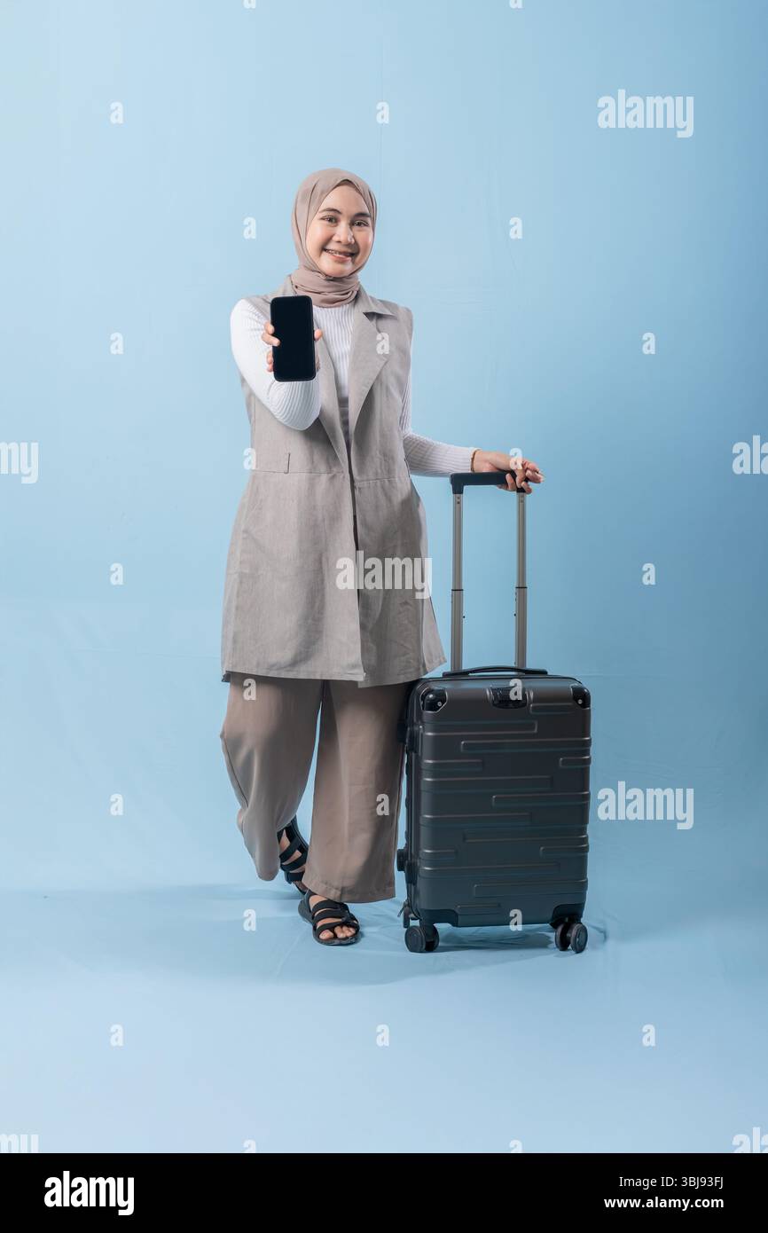 Eine Frau hält ein schwarzes Handy und zeigt darauf. Sie lächelt und ist glücklich Stockfoto