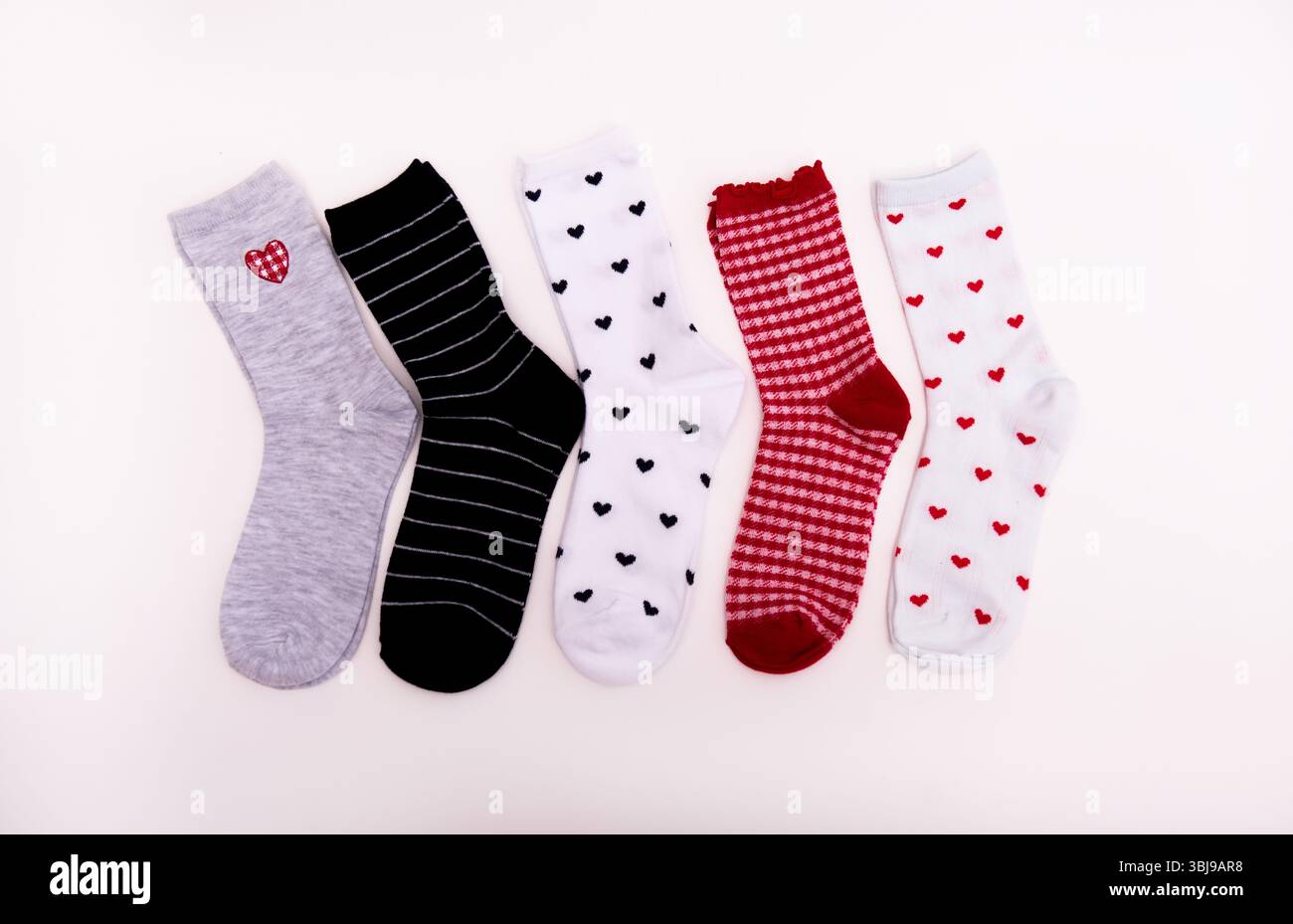 Verschiedene Socken mit Herzen sind auf weißem Hintergrund. Stockfoto