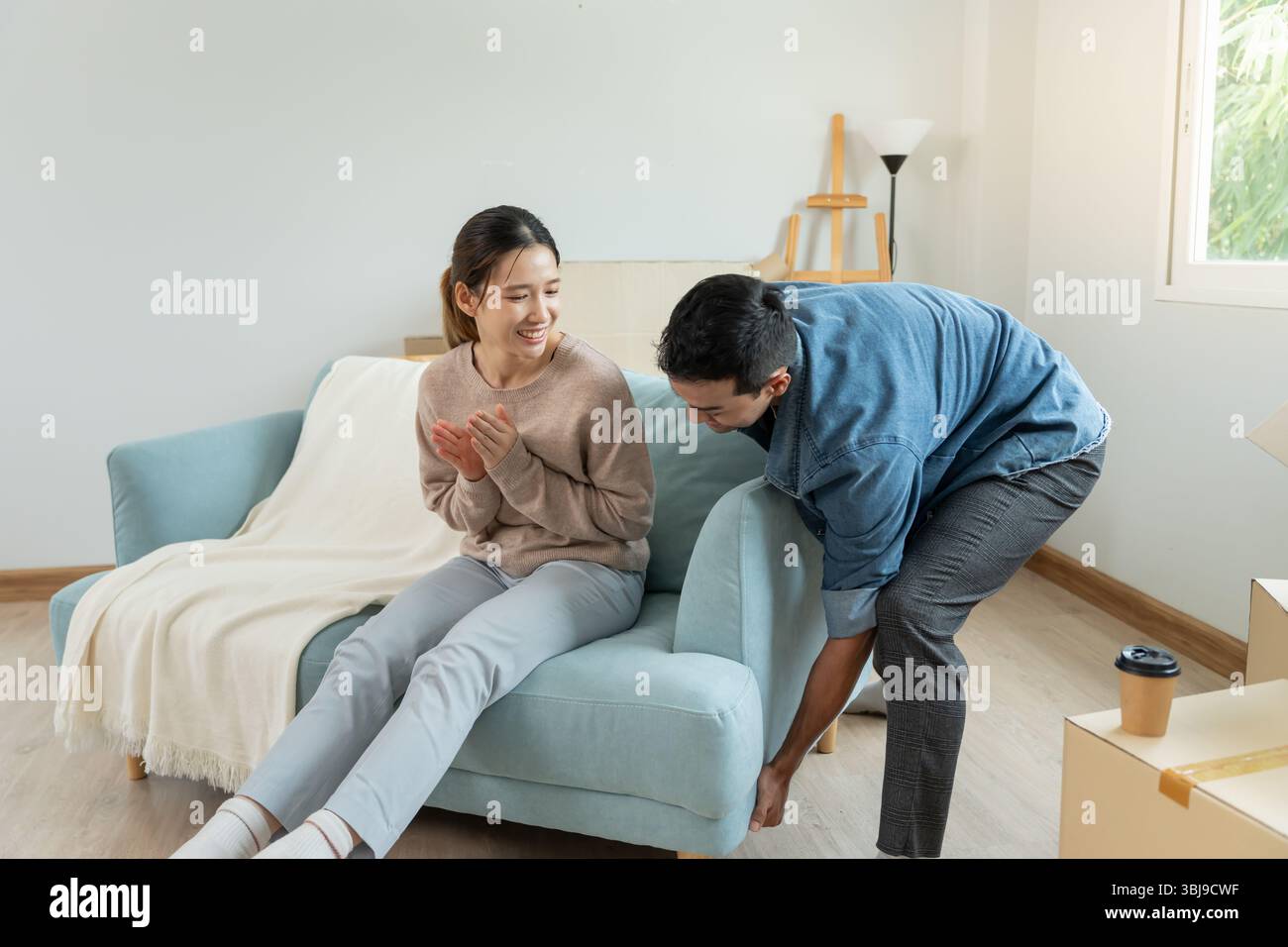 Umzug, Umzug. Die Frau fühlt sich gut und neckt ihren Mann, im Zimmer war eine Pappschachtel mit persönlichen Sachen und Möbeln Stockfoto