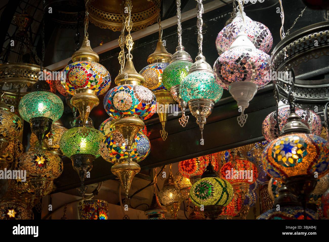 Mosaiklaternen in verschiedenen Farben schaffen eine lebendige Atmosphäre auf einem Istanbuler Markt, während der Abend näher rückt und lokale Handwerkskunst zeigt. Stockfoto