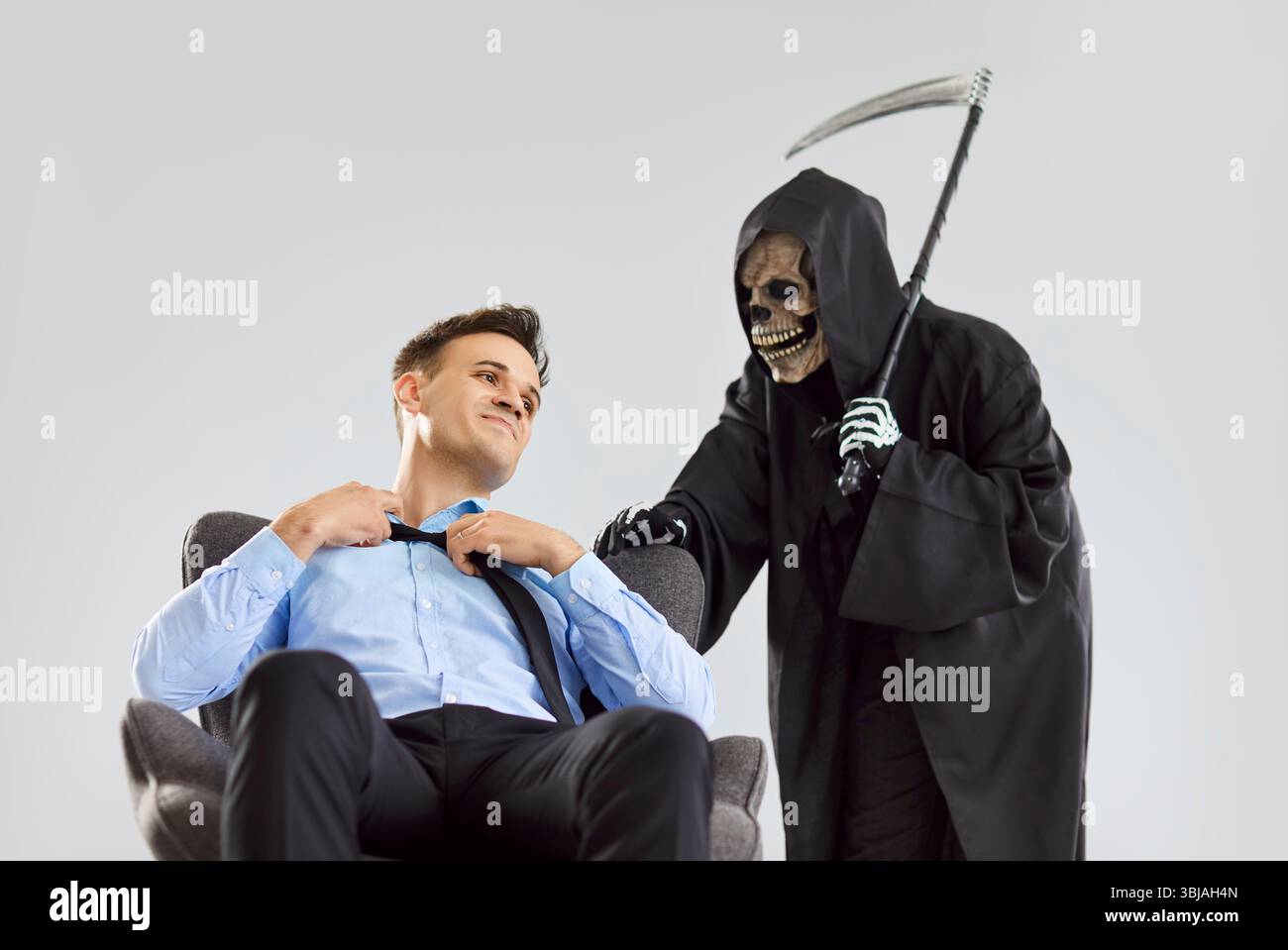 Tod, der zu einem jungen Mann kommt, neues Opfer findet, Panikattacke des Geschäftsmannes, schwarzer halloween-Sensenmann Stockfoto