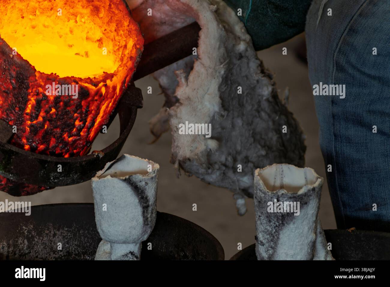 Geschmolzenes Metall aus Tiegelgießen in Keramikform beim Bronzeguss im Wachsverlustverfahren. Stockfoto