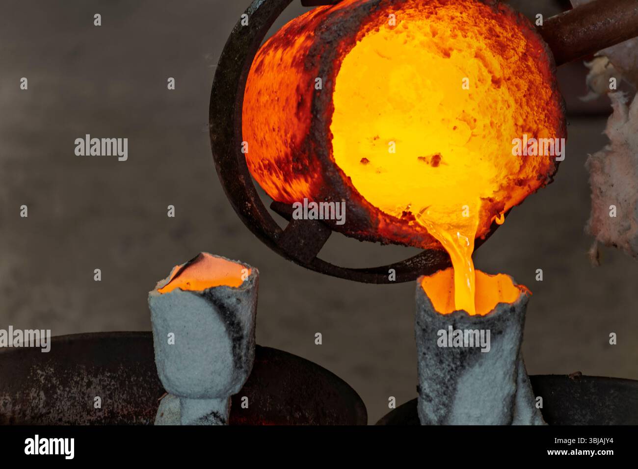 Geschmolzenes Metall aus Tiegelgießen in Keramikform beim Bronzeguss im Wachsverlustverfahren. Stockfoto