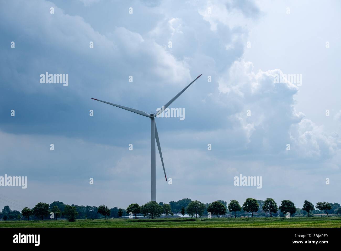 Blick auf eine ländliche Gegend mit einer Windturbine vor einem Himmel mit Sturmwolken Stockfoto